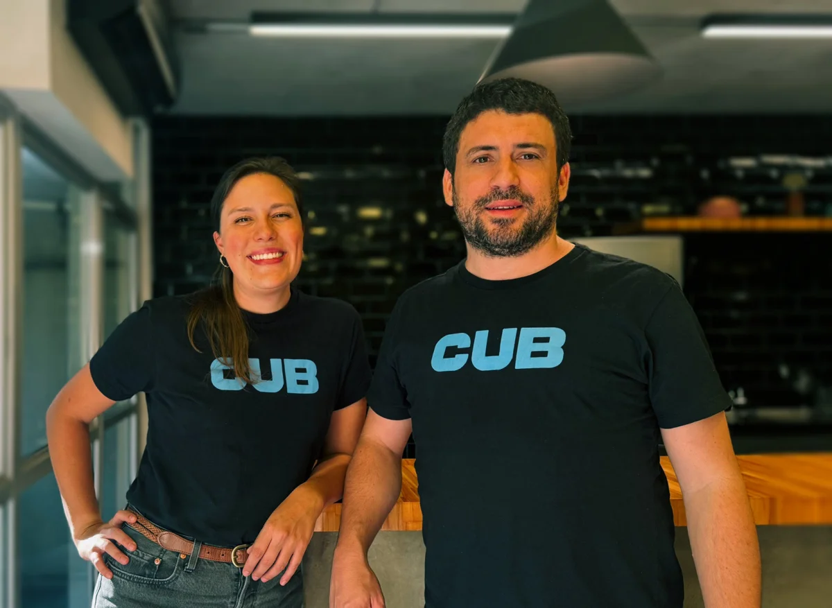Homem e mulher sorrindo usando camisetas pretas com logo azul CUB em ambiente interno moderno